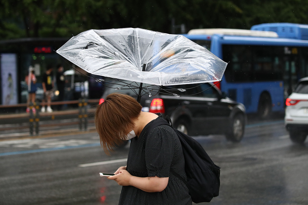 台风"海神"登陆韩国带来大风降雨 行人撑伞风中凌乱